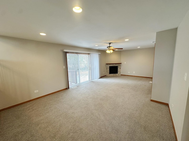 unfurnished living room featuring ceiling fan, a fireplace, and carpet