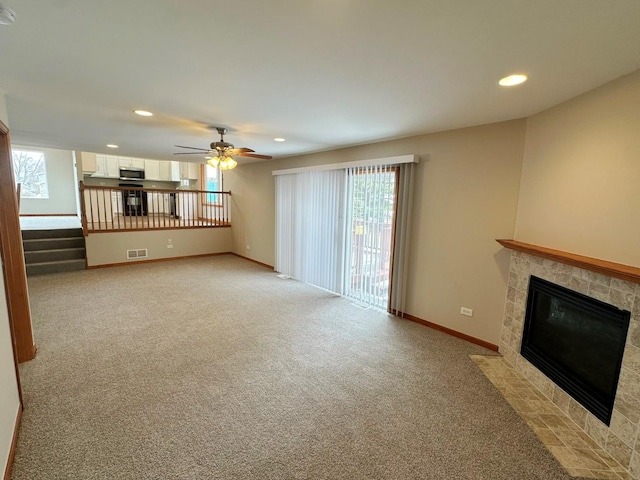 unfurnished living room with light carpet, a tile fireplace, and ceiling fan