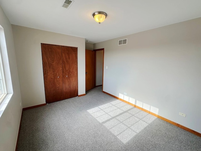 unfurnished bedroom with light colored carpet and a closet