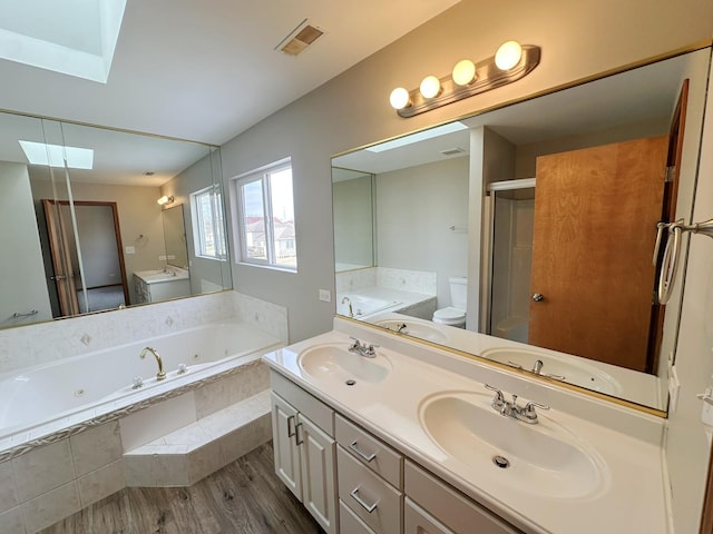 full bathroom featuring toilet, wood-type flooring, a skylight, vanity, and independent shower and bath