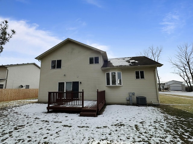 snow covered rear of property with a wooden deck and cooling unit