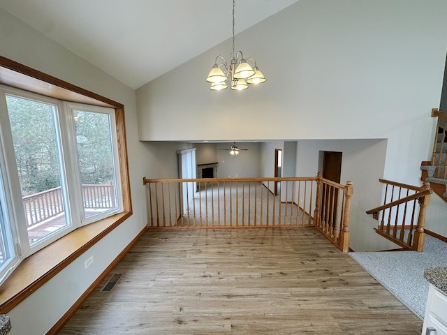 interior space with high vaulted ceiling, ceiling fan with notable chandelier, and light wood-type flooring