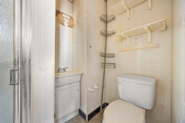 bathroom with tile patterned flooring, vanity, tile walls, and toilet