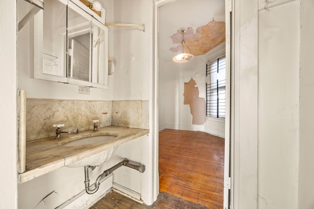 bathroom with sink, decorative backsplash, and hardwood / wood-style floors