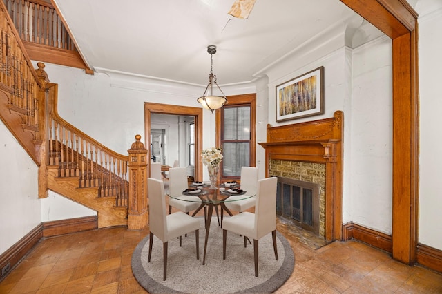 dining room with crown molding and a stone fireplace