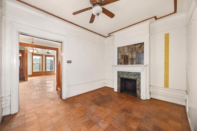 unfurnished living room with ceiling fan, parquet flooring, ornamental molding, and a tiled fireplace