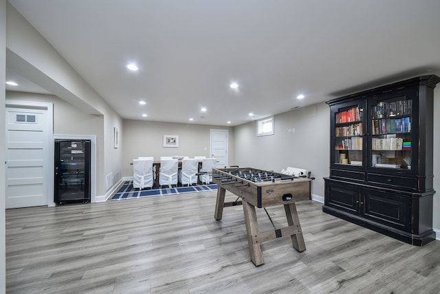 rec room with wine cooler and light hardwood / wood-style floors