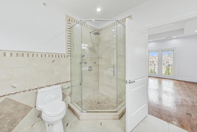 bathroom featuring tile patterned flooring, walk in shower, tile walls, and toilet