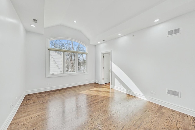 empty room with vaulted ceiling and light wood-type flooring