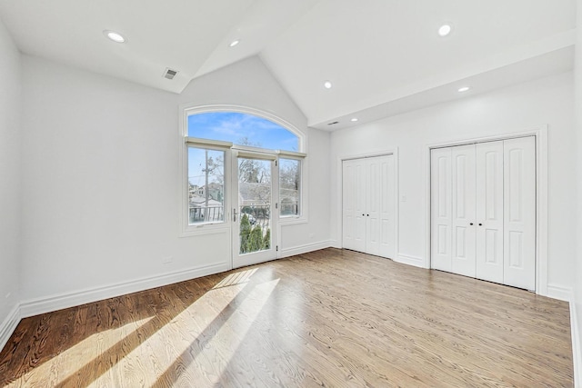 unfurnished living room featuring high vaulted ceiling and light hardwood / wood-style floors