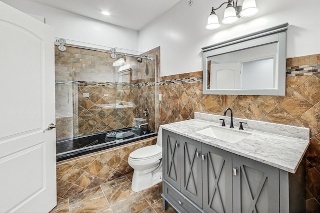 full bathroom featuring vanity, tile walls, enclosed tub / shower combo, and toilet