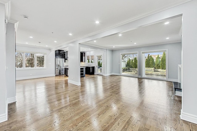 unfurnished living room featuring crown molding and wood-type flooring