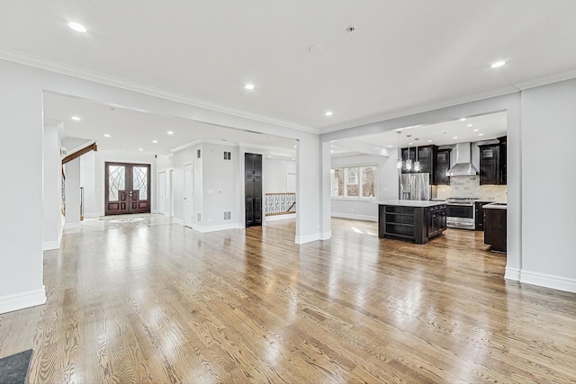 unfurnished living room with crown molding, plenty of natural light, elevator, and light hardwood / wood-style floors