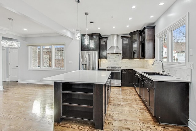 kitchen featuring pendant lighting, wall chimney range hood, sink, stainless steel appliances, and a center island