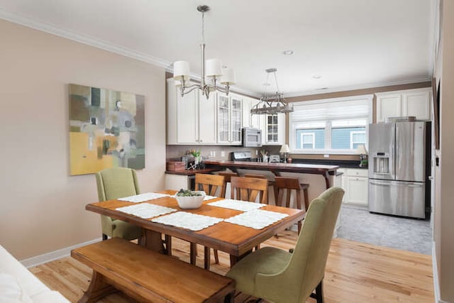 dining area with crown molding, an inviting chandelier, and light hardwood / wood-style floors