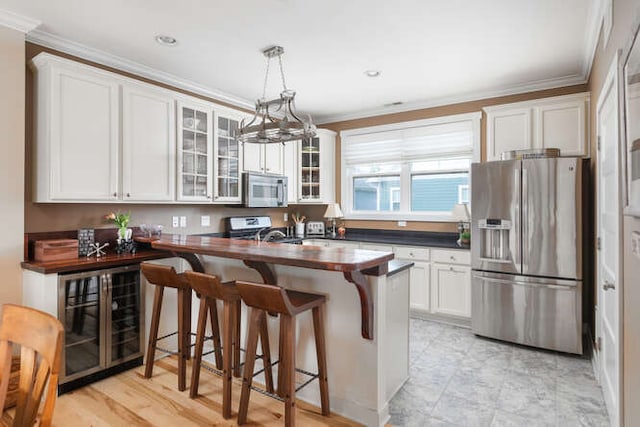 kitchen featuring a kitchen bar, hanging light fixtures, appliances with stainless steel finishes, kitchen peninsula, and white cabinets