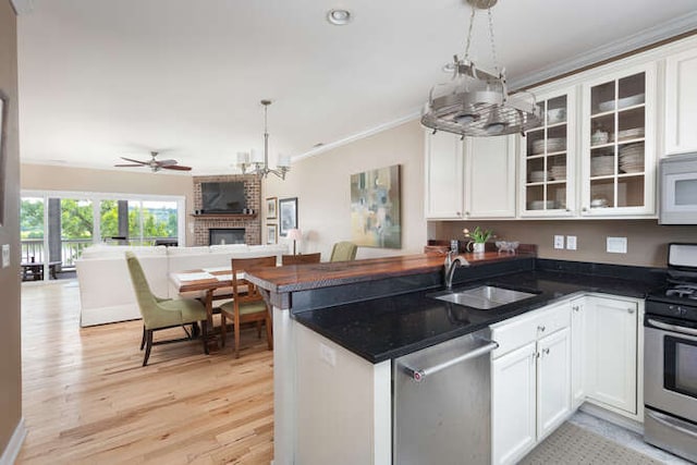 kitchen with sink, white cabinetry, hanging light fixtures, appliances with stainless steel finishes, and kitchen peninsula