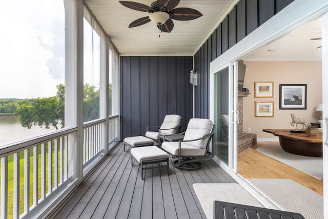 sunroom / solarium with ceiling fan and a water view