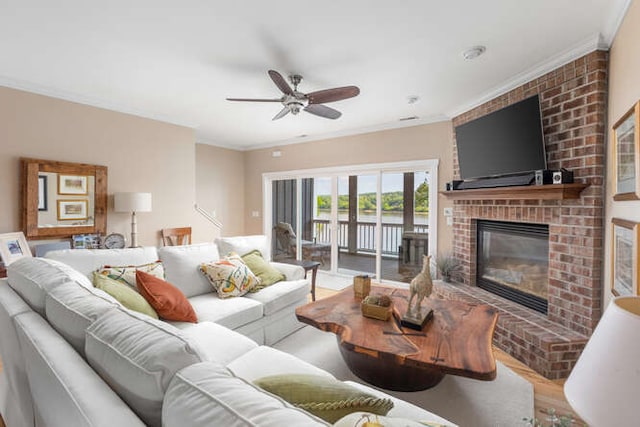 living room featuring crown molding, ceiling fan, wood-type flooring, and a brick fireplace