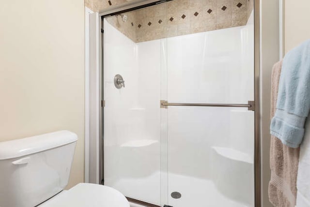 bathroom featuring a shower with shower door and toilet