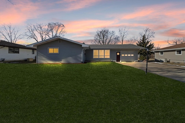 single story home featuring a garage and a lawn