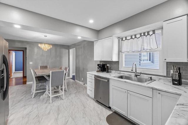 kitchen featuring pendant lighting, sink, appliances with stainless steel finishes, white cabinetry, and light stone counters