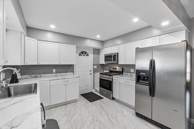 kitchen with light stone counters, sink, white cabinets, and appliances with stainless steel finishes