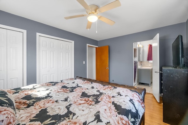 bedroom featuring ceiling fan, ensuite bath, light hardwood / wood-style flooring, and two closets