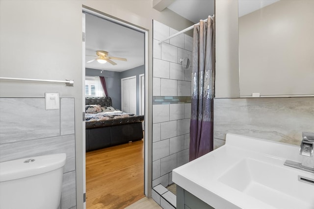 bathroom with ceiling fan, a shower with shower curtain, vanity, wood-type flooring, and toilet