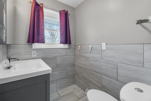 bathroom featuring vanity, tile walls, and toilet