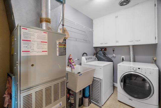 washroom featuring heating unit, cabinets, and washing machine and clothes dryer