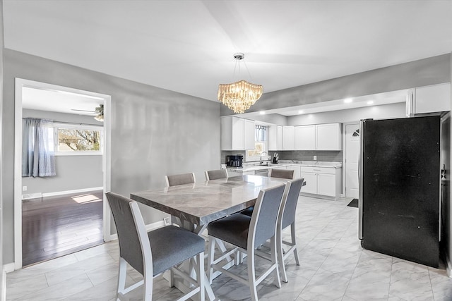 dining space featuring sink and ceiling fan with notable chandelier