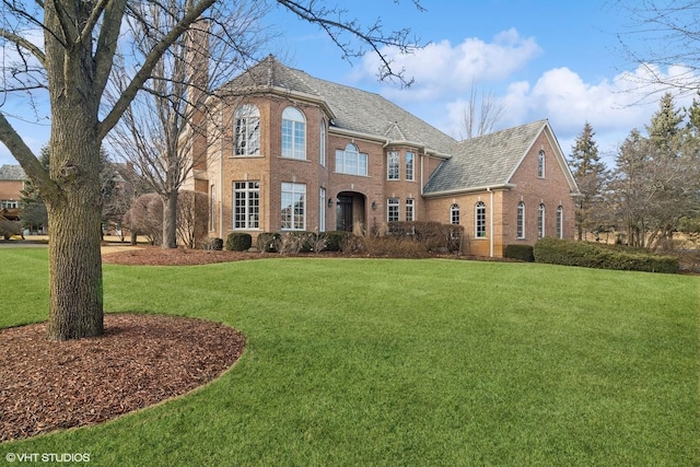 view of front of house featuring a chimney, a front lawn, and brick siding