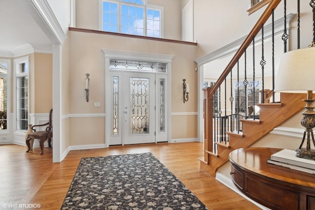 foyer with a towering ceiling, baseboards, and wood finished floors