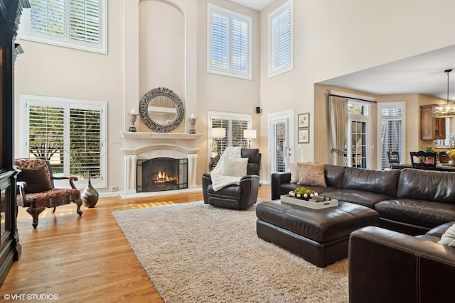 living room with a warm lit fireplace, plenty of natural light, and light wood finished floors