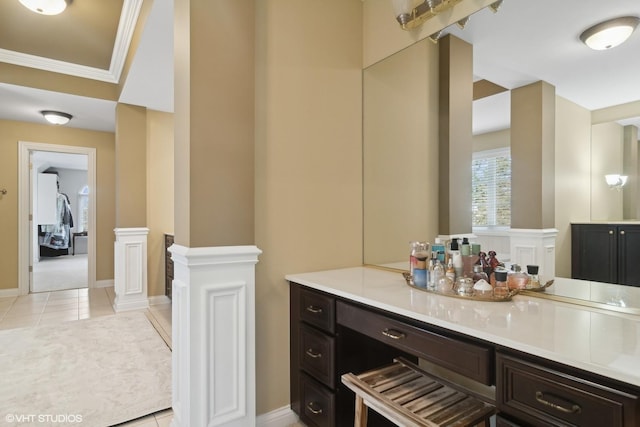 bathroom featuring tile patterned flooring, crown molding, vanity, and baseboards