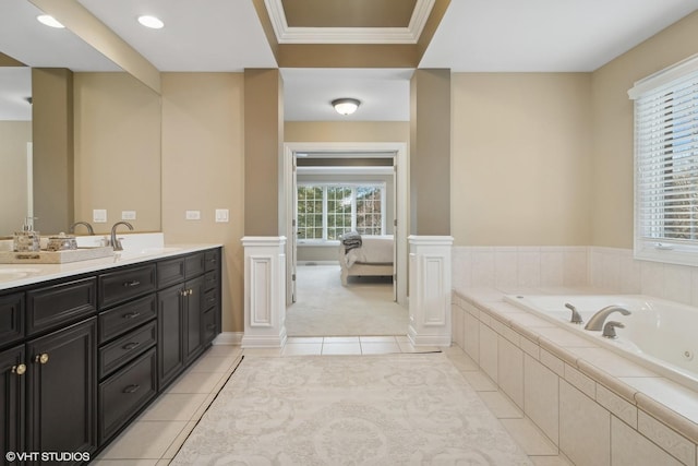 ensuite bathroom featuring a garden tub, a sink, tile patterned floors, ensuite bath, and decorative columns