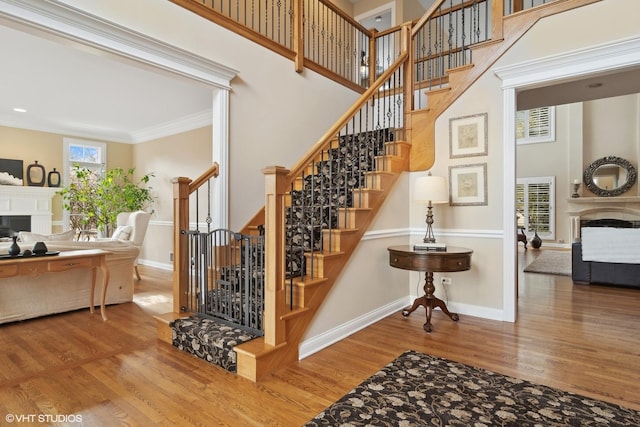 stairway with a high ceiling, a fireplace, and wood finished floors