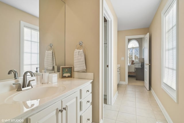 bathroom featuring baseboards, ensuite bathroom, vanity, and tile patterned floors