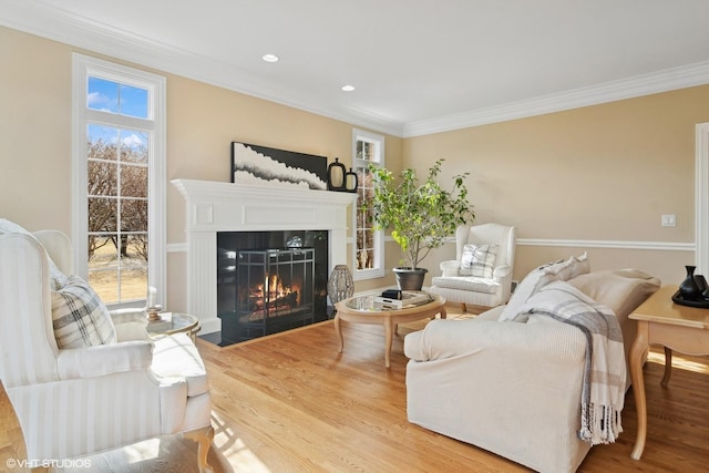 living room featuring wood finished floors, a fireplace with flush hearth, a wealth of natural light, and crown molding