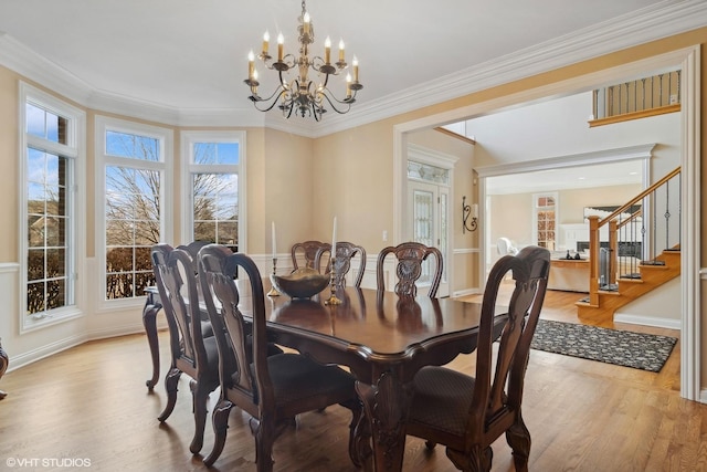 dining space featuring ornamental molding, stairs, an inviting chandelier, and wood finished floors