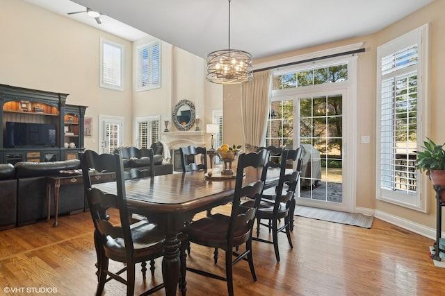 dining room with a notable chandelier, a fireplace, baseboards, and wood finished floors