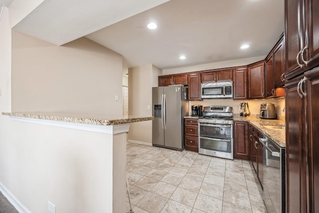 kitchen featuring dark brown cabinetry, appliances with stainless steel finishes, light stone countertops, and kitchen peninsula