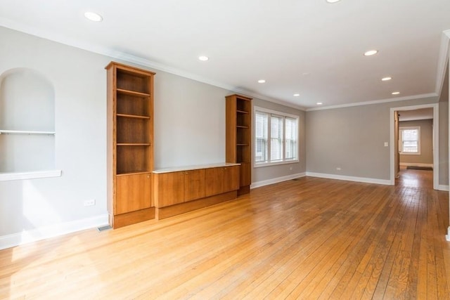 empty room with light wood-style flooring, a wealth of natural light, and crown molding