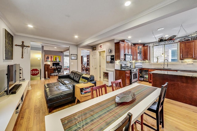 dining area with light wood-style flooring, ornamental molding, and recessed lighting