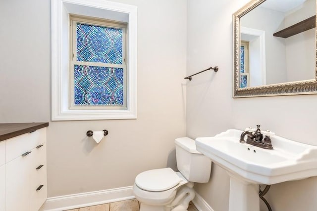 half bath featuring toilet, a sink, and baseboards