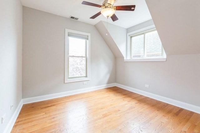 bonus room featuring visible vents, light wood finished floors, lofted ceiling, and a healthy amount of sunlight