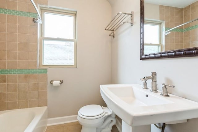 bathroom with bathing tub / shower combination, tile patterned flooring, toilet, a sink, and baseboards