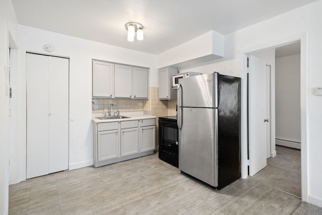 kitchen featuring sink, stainless steel refrigerator, a baseboard heating unit, tasteful backsplash, and black electric range