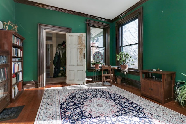 sitting room with crown molding and dark wood-type flooring